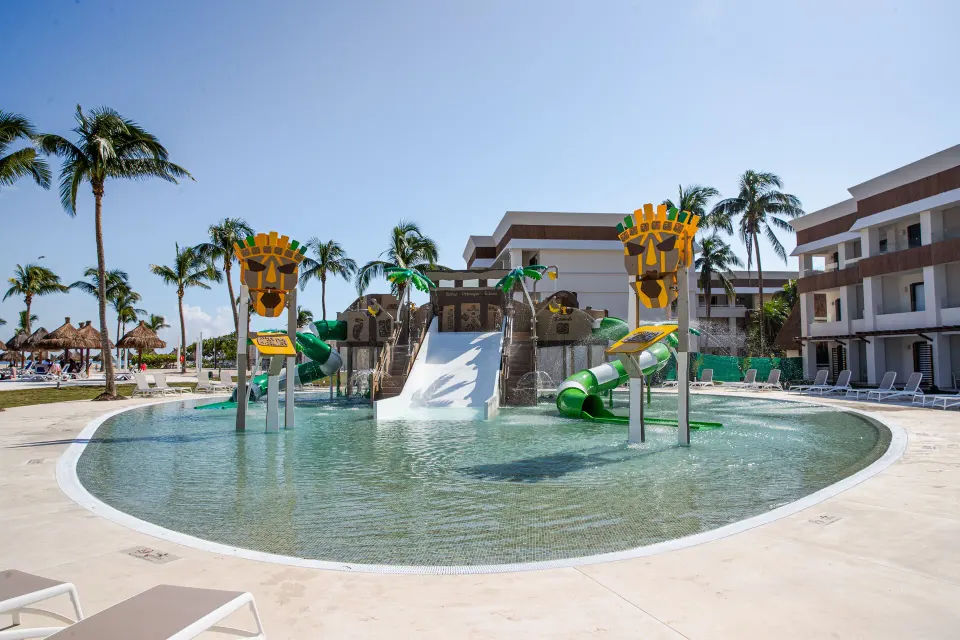 Children's splash pool with green slides and shallow water at Bahia Principe Grand Tulum