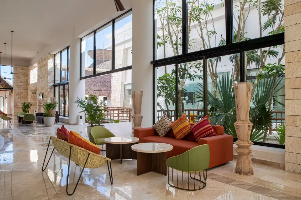 Lobby lounge with modern chairs and a view to an inner garden at Bahia Principe Grand Tulum