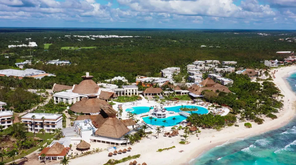 Aerial view of Bahia Principe Grand Tulum resort showing pools, thatched roofs and beachfront.