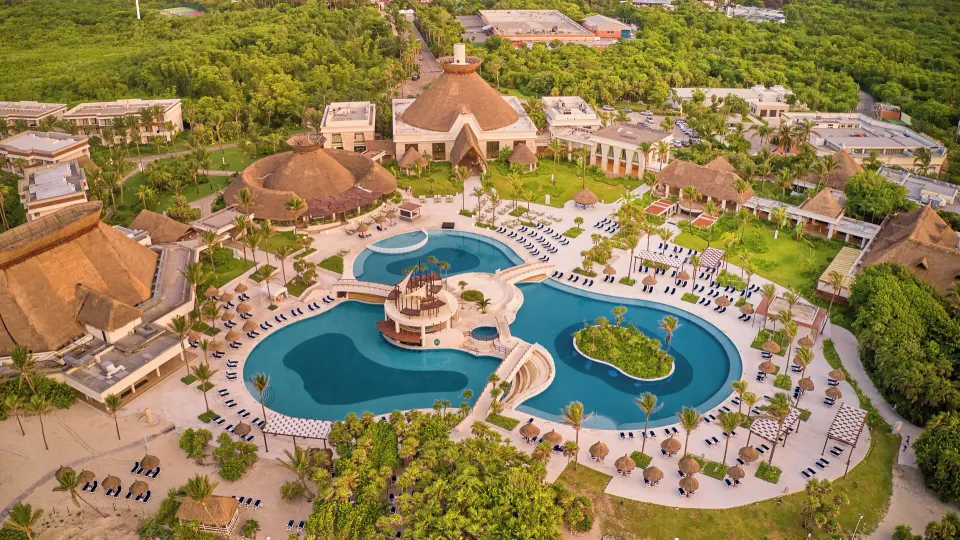 Aerial view of resort grounds, pools and thatched-roof buildings at Bahia Principe Grand Tulum