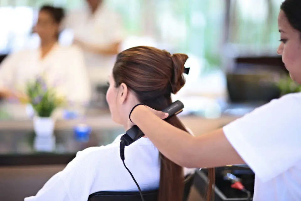 Spa therapist using a hot tool on a guest's hair at Bahia Principe Grand Tulum