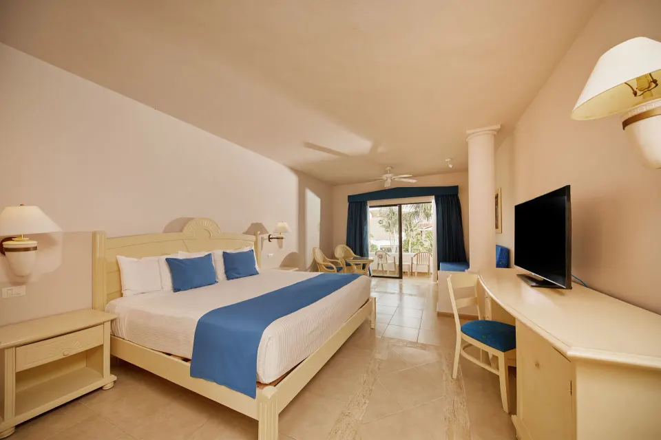 Bright king bedroom with blue accents at Bahia Principe Grand Tulum