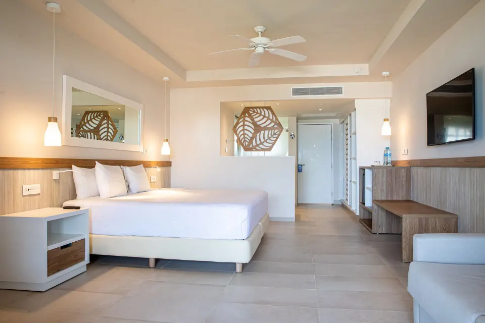 King bed and seating area in a bright guest room at Bahia Principe Grand Tulum