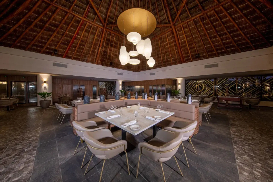 Central table grouping under large chandelier in resort restaurant at Bahia Principe Grand Tulum