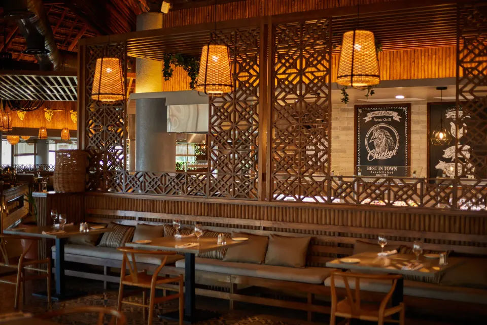 Warm-toned restaurant interior with lattice wood screens and pendant lamps at Bahia Principe Grand Tulum