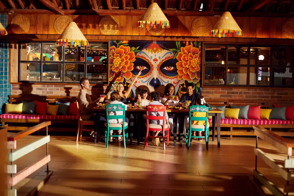 Group dining at a long table beneath a colorful Day of the Dead mural at Bahia Principe Grand Tulum