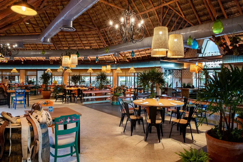 Spacious open-air dining room with colorful chairs and hanging lights at Bahia Principe Grand Tulum