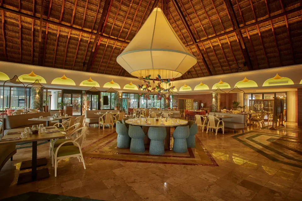 Spacious palapa-roof dining room with central chandelier at Bahia Principe Grand Tulum