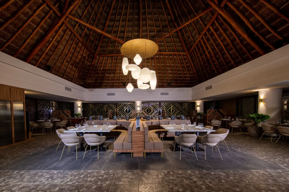 Elegant thatched-roof dining interior with pendant lights at Bahia Principe Grand Tulum
