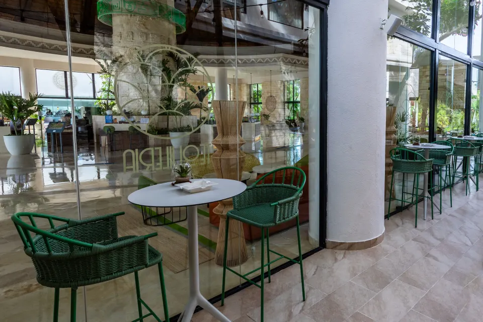 Small tables and green chairs outside the lobby bar at Bahia Principe Grand Tulum