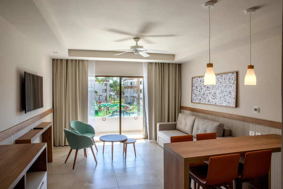 Living and dining area of a 2 Bedroom Suite at Bahia Principe Grand Tulum with balcony view