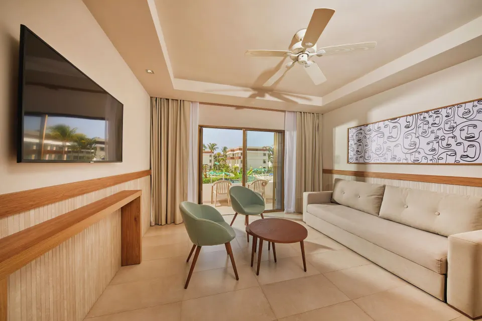 Family Suite sitting area with sofa, chairs and TV at Bahia Principe Grand Tulum