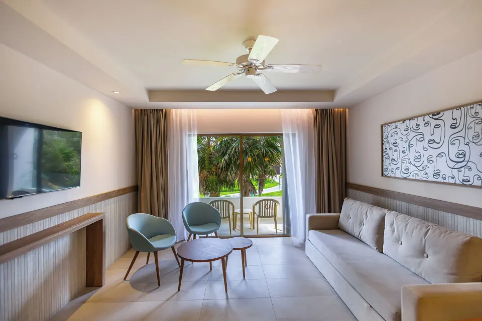 Junior Suite sitting area with sofa, chairs and balcony at Bahia Principe Grand Tulum