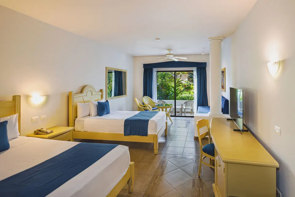 Spacious junior suite with two beds, desk, seating area and balcony at Bahia Principe Grand Tulum