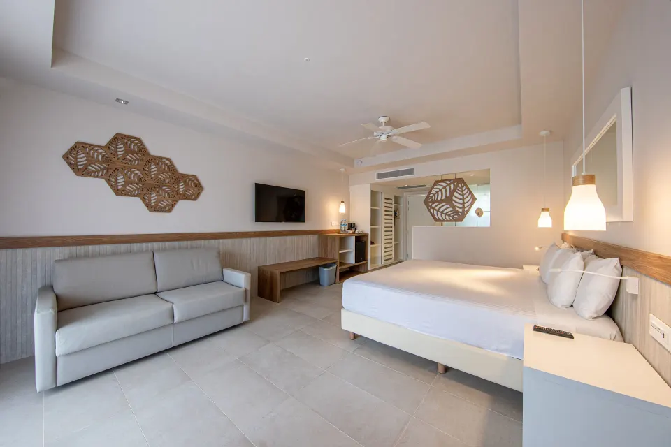 Premium Room (Superior 2+2) interior showing sofa, TV and king bed at Bahia Principe Grand Tulum