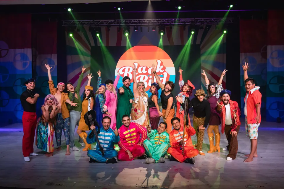 Colorful resort performers posing onstage during a show at Bahia Principe Grand Tulum