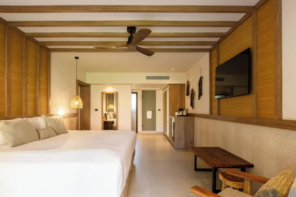 Spacious guest suite with king bed and wood accents at Bahia Principe Luxury Akumal