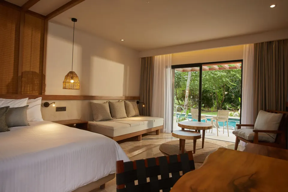 Modern king bed and daybed with sliding glass doors to a garden at Bahia Principe Luxury Akumal.