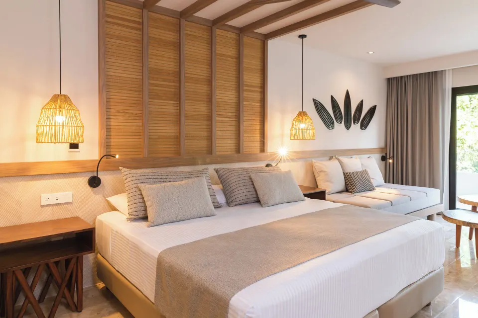 Well-lit bedroom with king bed, bench seating and pendant lamps at Bahia Principe Luxury Akumal