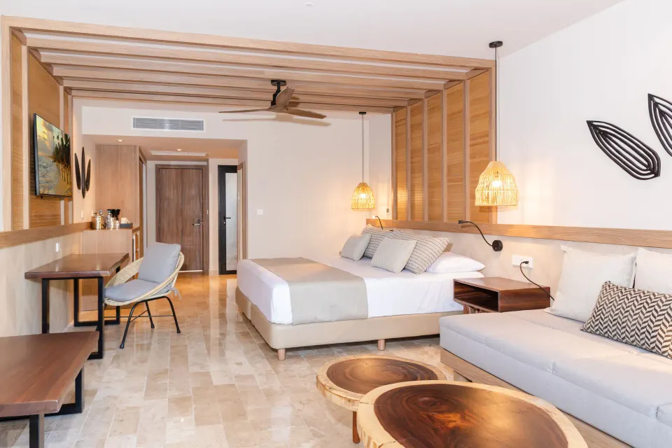 Open-plan room with king bed, work desk and rounded wooden coffee tables at Bahia Principe Luxury Akumal