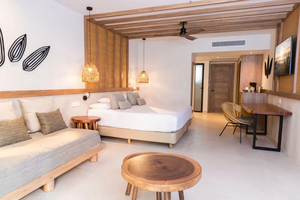 Contemporary suite with king bed, sofa and wooden stools at Bahia Principe Luxury Akumal