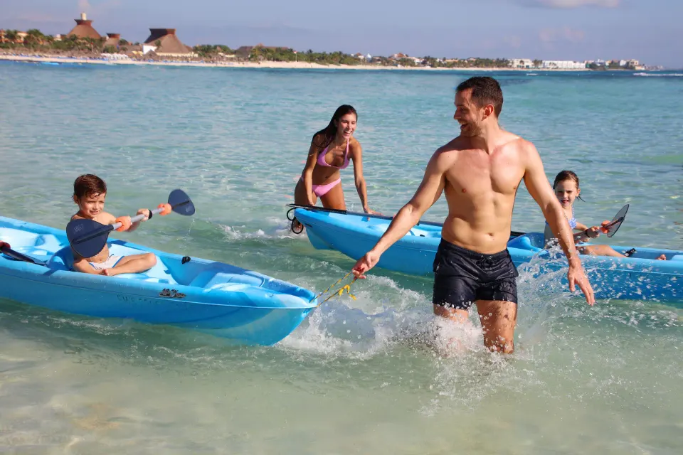 Family enjoying kayaks in the shallow water at Bahia Principe Luxury Akumal