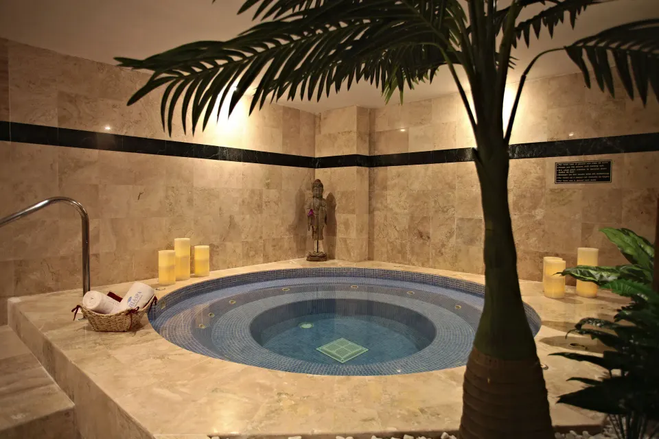 Indoor circular spa tub with candles and tiled walls at Bahia Principe Luxury Akumal.