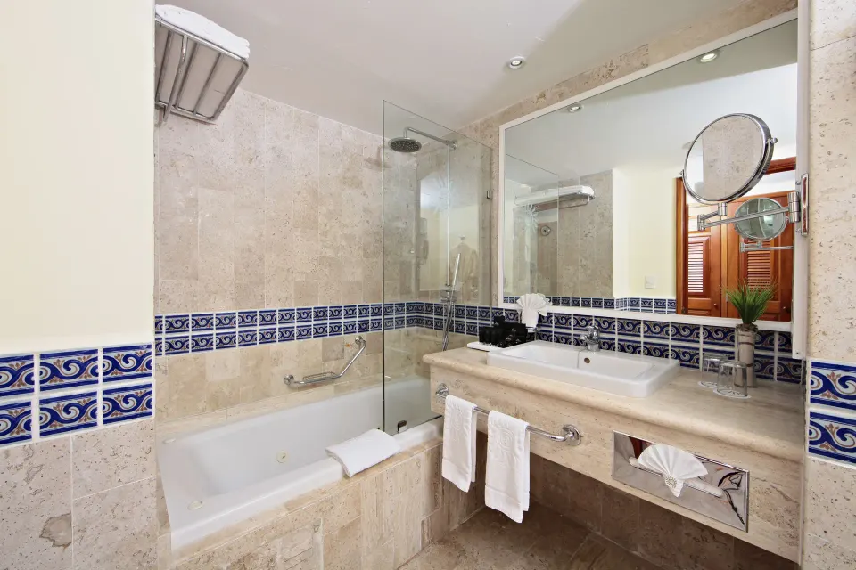 Hotel bathroom with tub, vanity and decorative blue tile border at Bahia Principe Luxury Akumal