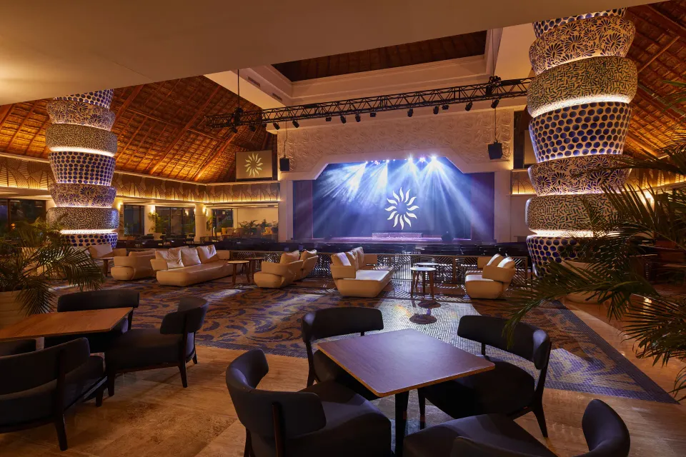 Resort lobby lounge area with raised stage and seating at Bahia Principe Luxury Akumal