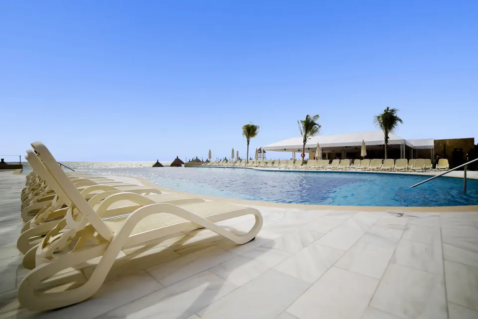 Poolside loungers lined up beside the oceanfront pool at Bahia Principe Luxury Akumal.