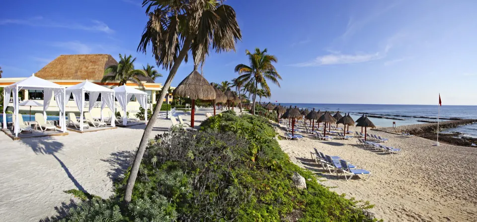 Resort beach with cabanas, palapas and loungers beside the sea at Bahia Principe Luxury Akumal