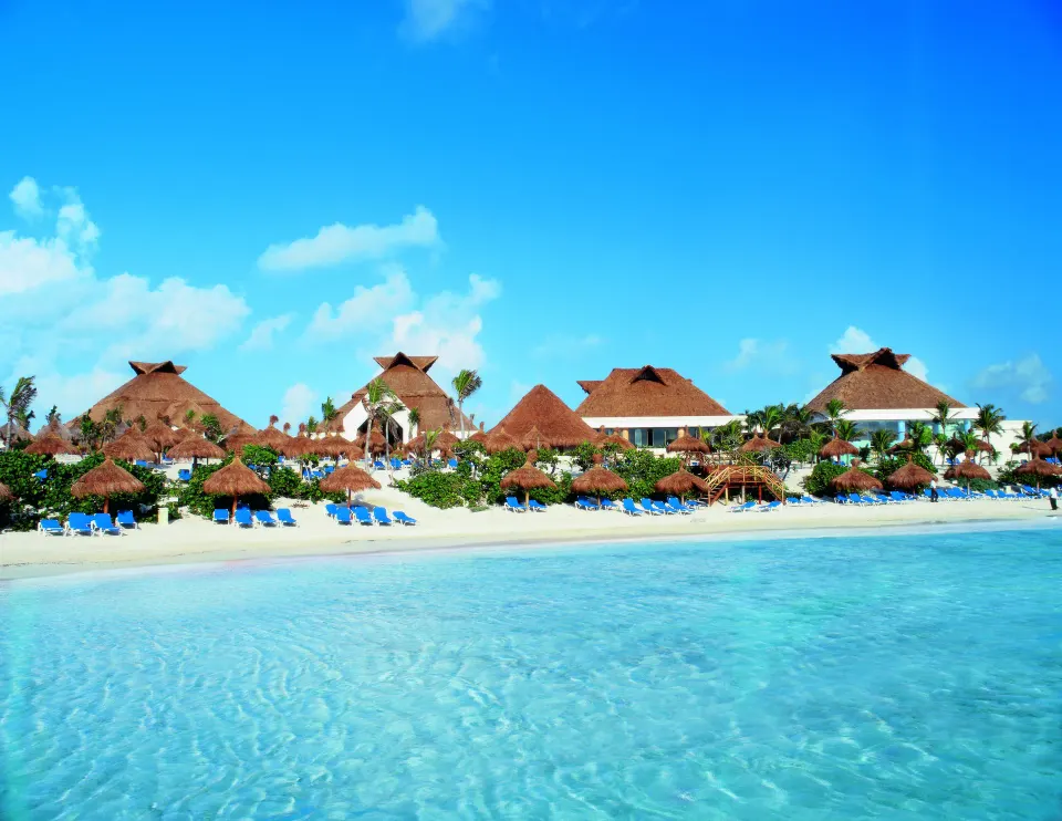 Beachfront with palapas and lounge chairs on white sand at Bahia Principe Luxury Akumal