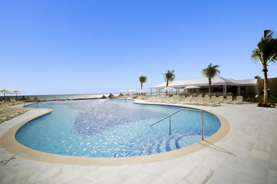 Round pool by the sea with steps and handrail at Bahia Principe Luxury Akumal.