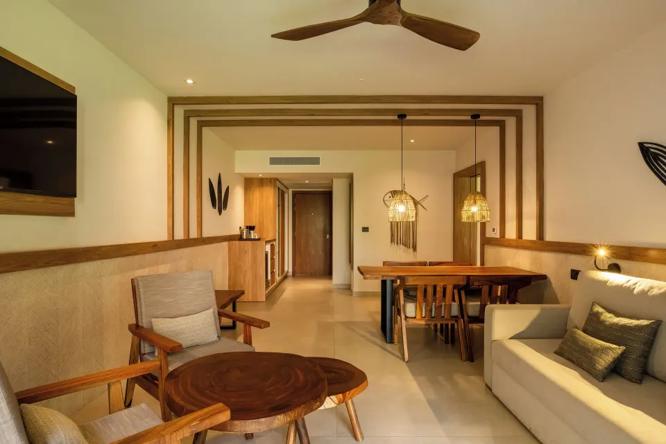 Seating area and dining table in a junior suite at Bahia Principe Luxury Akumal