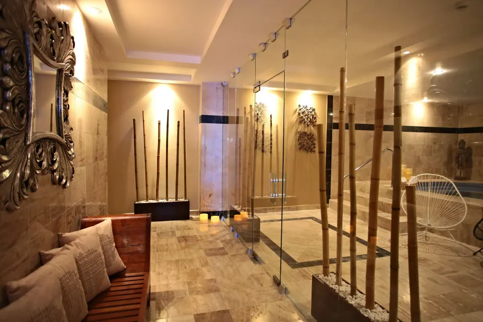 Glass-walled spa entry with wooden bench and decorative bamboo at Bahia Principe Luxury Akumal