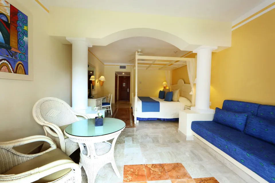 Open suite with canopy bed, sofa and wicker table at Bahia Principe Luxury Akumal