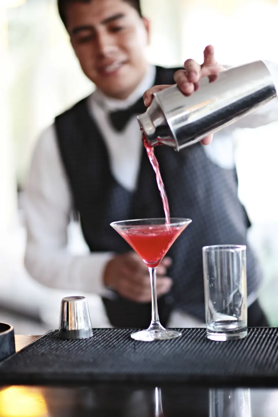Bartender pouring a red cocktail into a martini glass at Bahia Principe Luxury Akumal