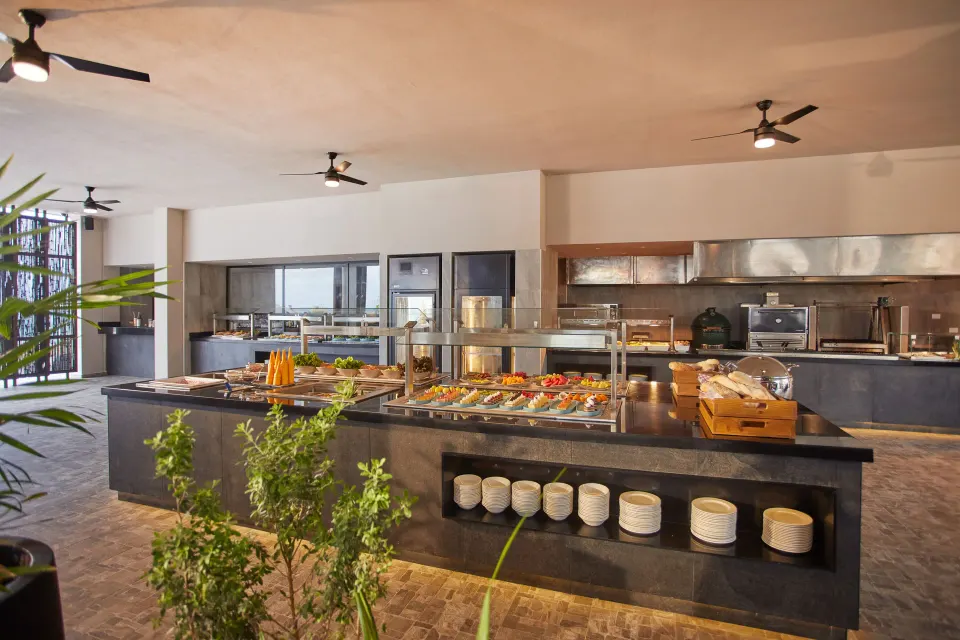 Buffet island with plated salads and serving stations in a casual dining area at Bahia Principe Luxury Akumal