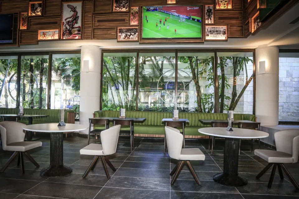 Tables and chairs by windows with TVs above at Bahia Principe Luxury Akumal