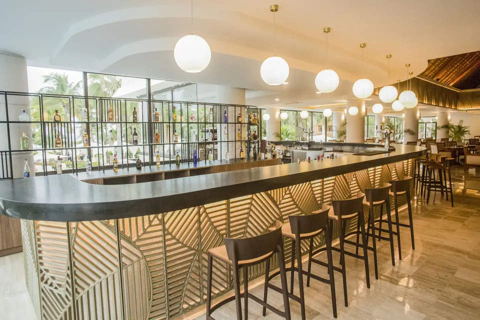 Long curved indoor bar with stools at Bahia Principe Luxury Akumal