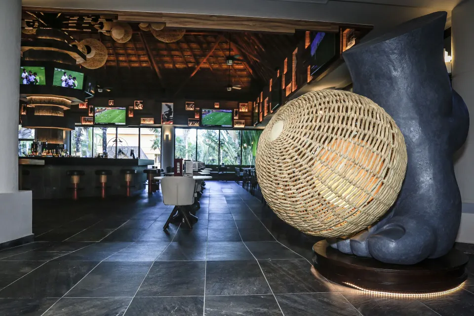 Dark entryway with sculptural décor and bar beyond at Bahia Principe Luxury Akumal