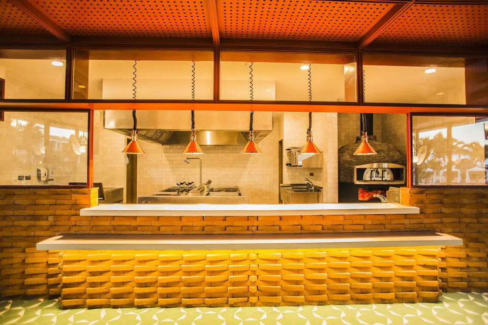 Kitchen pass with hanging heat lamps and brick front at Bahia Principe Luxury Akumal