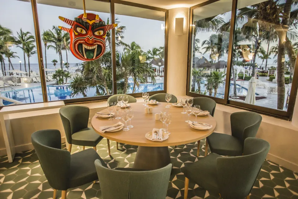 Round table by window with ocean and pool view at Bahia Principe Luxury Akumal