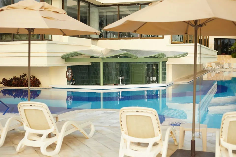 Swim-up pool bar with submerged seating and sun loungers at Bahia Principe Luxury Akumal.