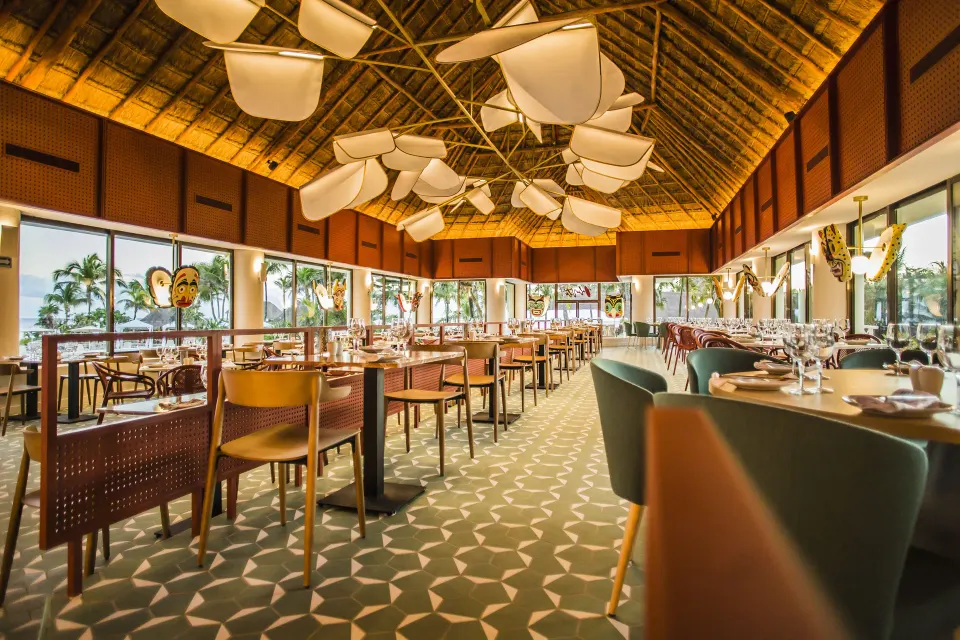 Wide-angle view of a palapa dining room with patterned carpet and decorative lighting at Bahia Principe Luxury Akumal