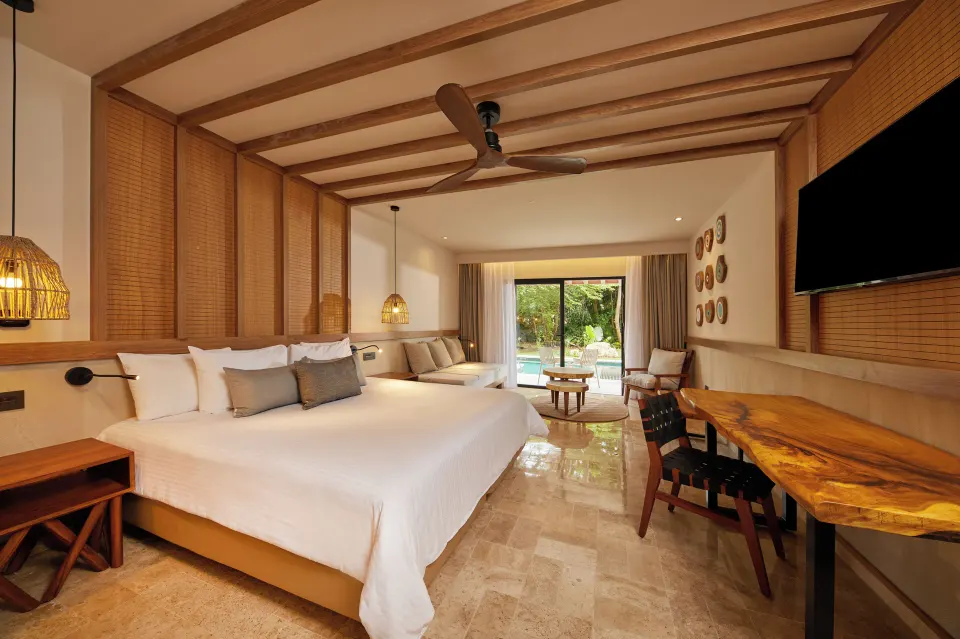 Junior Room Deluxe Swim Up king bed with wooden desk and pool view at Bahia Principe Luxury Akumal