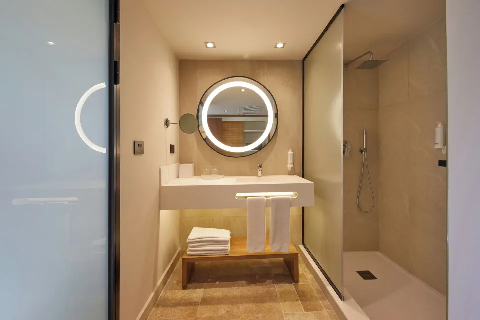 Vanity and shower view with round backlit mirror and walk-in shower at Bahia Principe Luxury Akumal