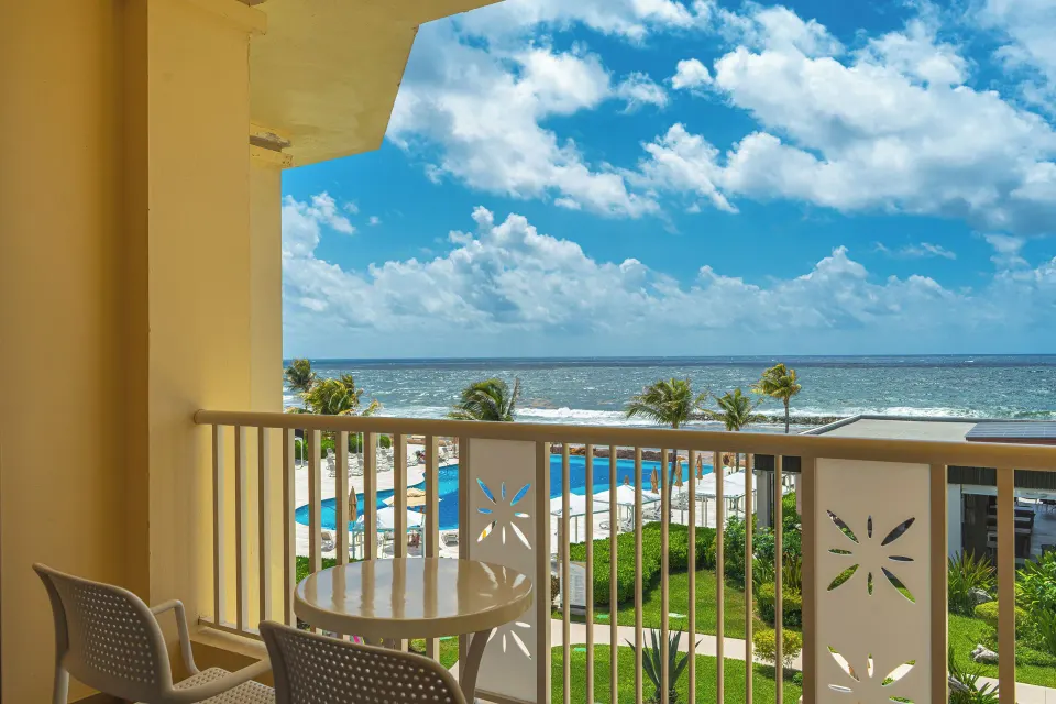 Balcony table with chairs and pool and ocean view at Bahia Principe Luxury Akumal