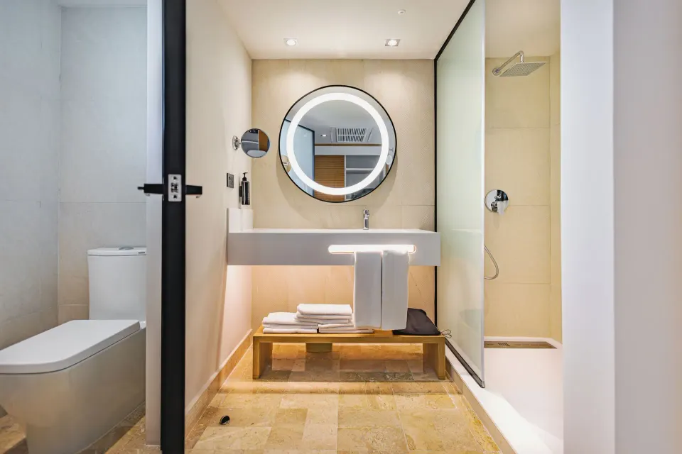 Bathroom vanity, round mirror and shower in a Junior Suite at Bahia Principe Luxury Akumal