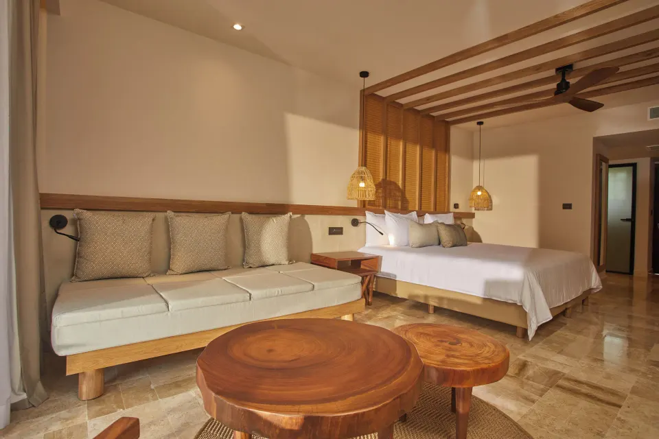 Wide view of junior suite showing bed and wooden coffee table at Bahia Principe Luxury Akumal